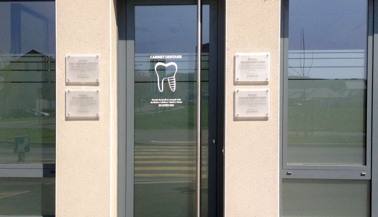 L'entrée du cabinet, avec les plaques des praticiens de part et d'autre de la porte